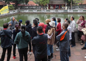 Group of tourists standing by a scenic lake with a traditional building